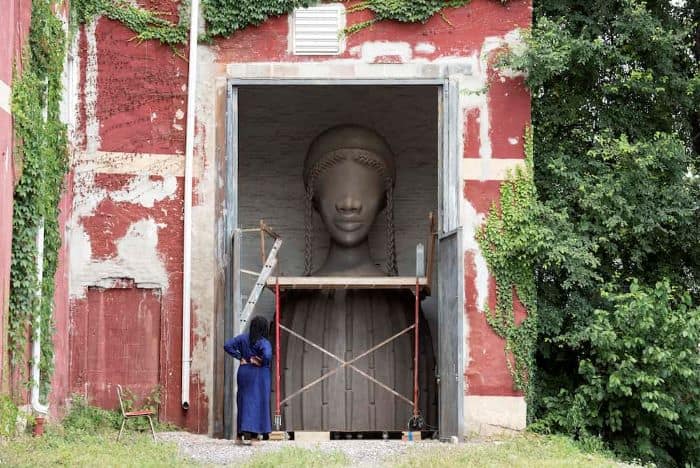 Simone Leigh, one of the award winning 2022 Venice Biennale artists, gazing at her sculpture Brick House while in progress.